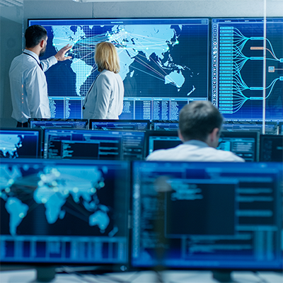 People working in front of large screens and maps at a command center.